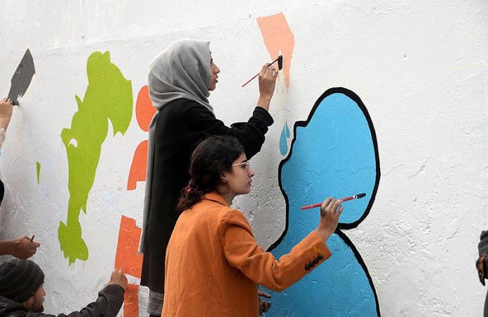 Students of Punjab University painting on the wall in connection with Polio Awareness Campaign in Liberty Chowk.
