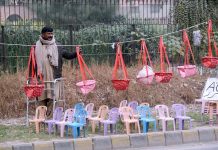 A seller displays AC covers, plastic chairs and children's bouncers to attract customers along Dhandi Road