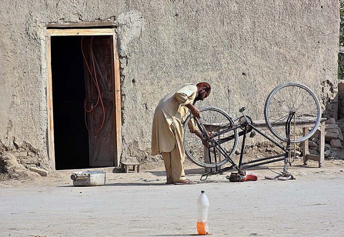 A vendor repairing cycle at his workplace near Chandka Medical College Colony