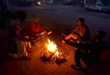 People are getting themselves warm with wood fire as temperature falls in the city.