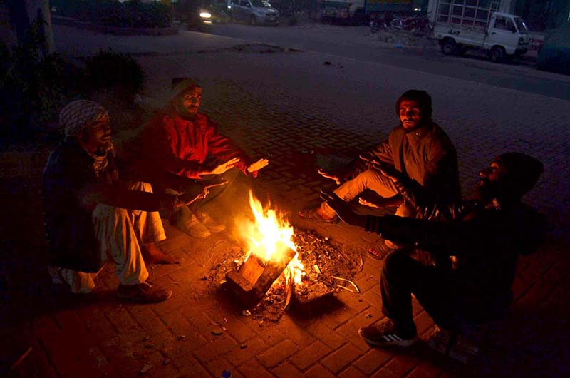 People are getting themselves warm with wood fire as temperature falls in the city.
