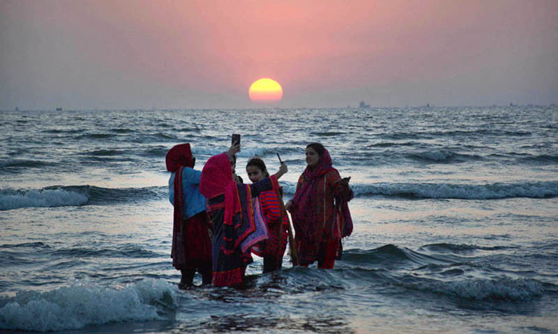 Girls taking selfies to preserve their memories as the sunset of year-2022 at sea view