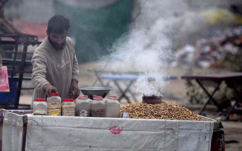 A vendor is displaying and selling warm peanuts at his cart during winter season at G-7 Markaz.