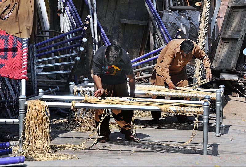 Labourers knitting the traditional bed (Charpai) for the customers at their workplace