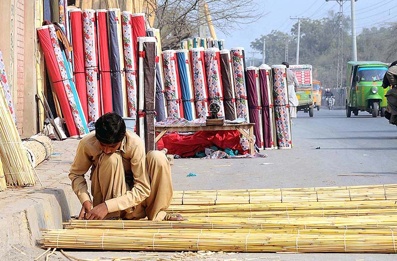 A worker making traditional curtains (Chick) at his roadside setup