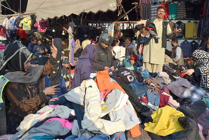 A seller is calling out buyers to buy warm clothes at a lower price in Landar Bazaar