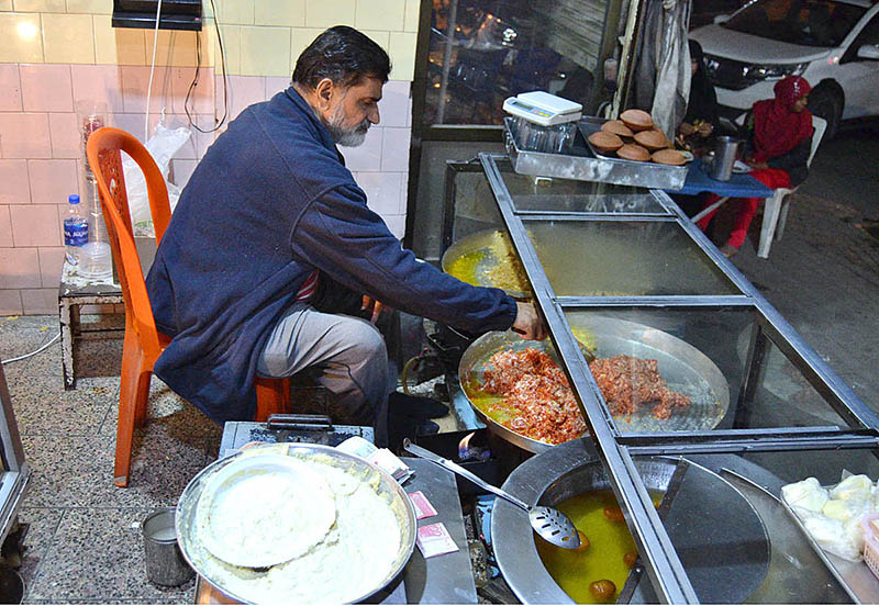 Shopkeeper selling traditional winter sweet dish Halwa and gulab jamun at Lakshmi Chowk Food Street