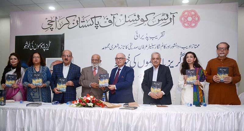 Famous Columnist and author Senator Irfan Siddiqui holds his book titled Gurez Paa Mosamoon ki Khushboo at the launching ceremony along with seasoned journalist Mehmood Sham and others at Arts Council.