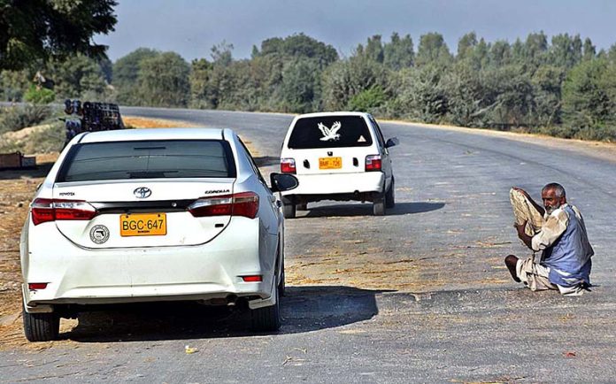 A beggar is begging from commuters in the middle of Larkana-Khairpur road near Fareedabad Village