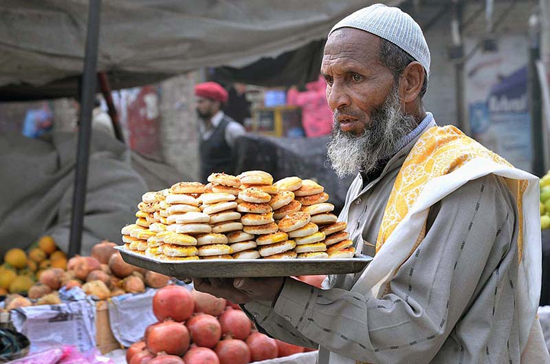 An elderly street vendor carrying and selling biscuits at Garhi Shahu