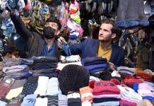 Vendor selling and displaying warm garments for winter season to attract customers at his setup