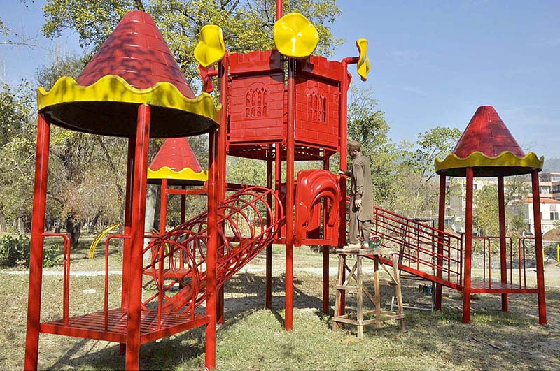 A worker busy in paint the slide in a local park in Federal Capital