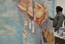 An artist giving final touch to a painting on IMCG F-6 school wall for maintaining beautification of the Federal Capital.