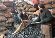 A shopkeeper filling sacks with coal to sell it to consumers as demand increased due to low pressure and shortage of gas during winter season