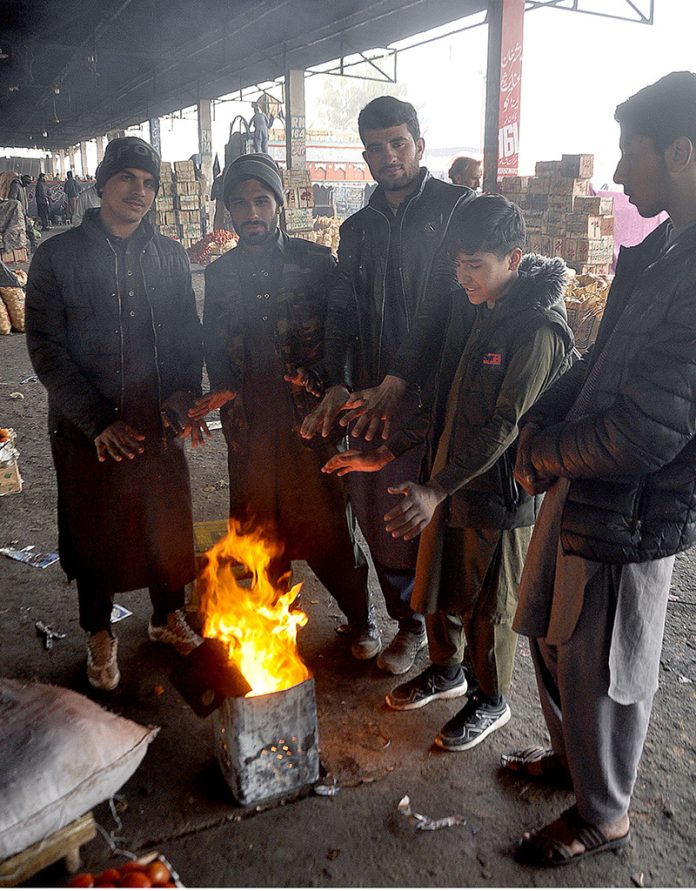 People standing around fire, warming themselves as the temperature dropped in Federal Capital