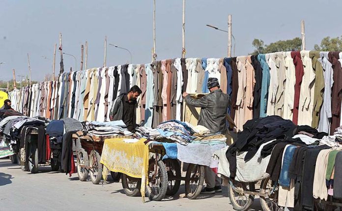 A customer busy in selecting and purchasing second hand clothes from a vendor at Khanna Pul