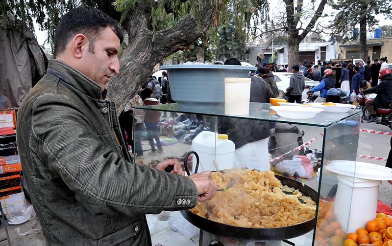 A vendor preparing and selling sweet dish (halwa) at his roadside setup