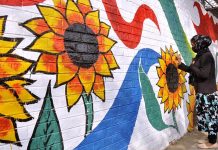 Girl busy painting on wall to enhance the beatification of Capital City