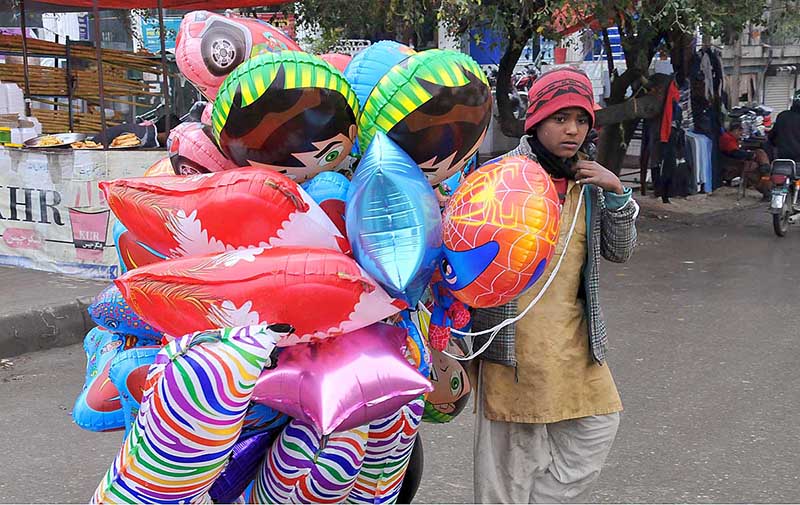 A young street vendor selling colorful balloons at G-9 Markaz