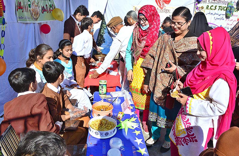 Visitors purchasing different traditional food from displayed food stall during Food Festival at Royal Cambridge School