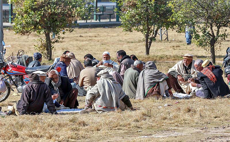 Elderly people busy in playing cards to spend their time while sitting on greenbelt along Kuri Road