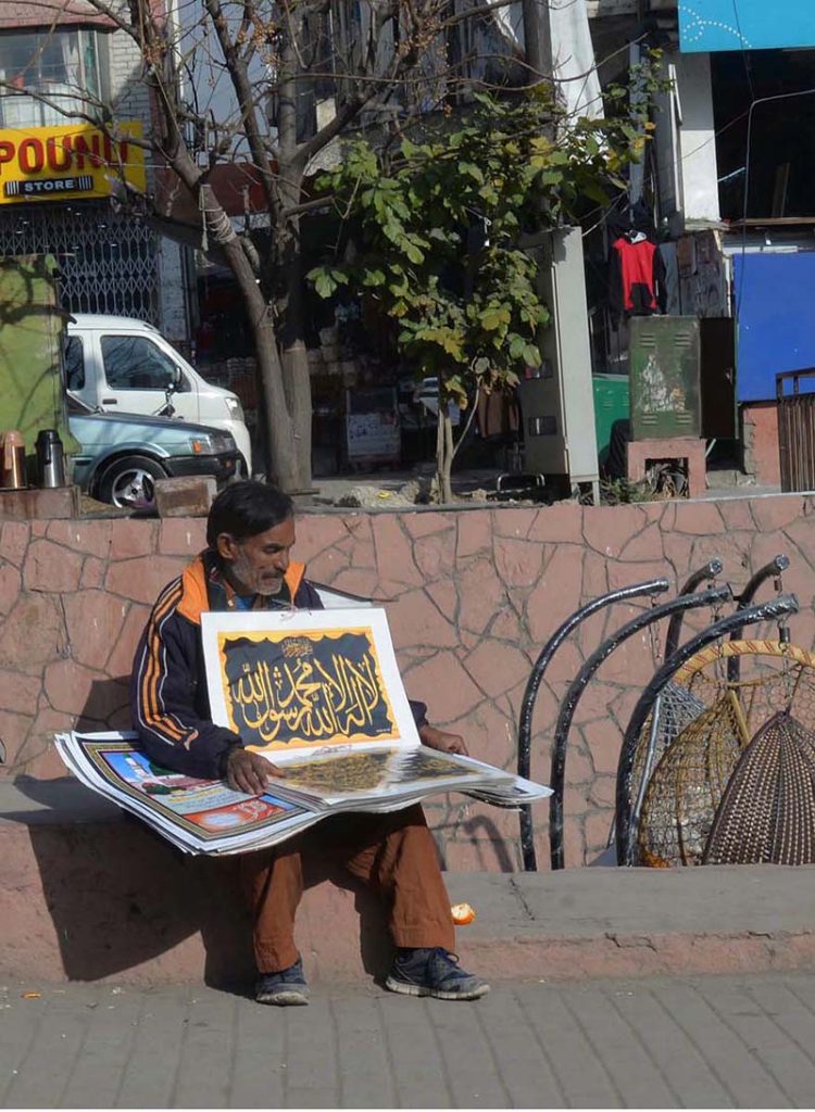 A street vendor selling Islamic posters on a footpath at Karachi Company