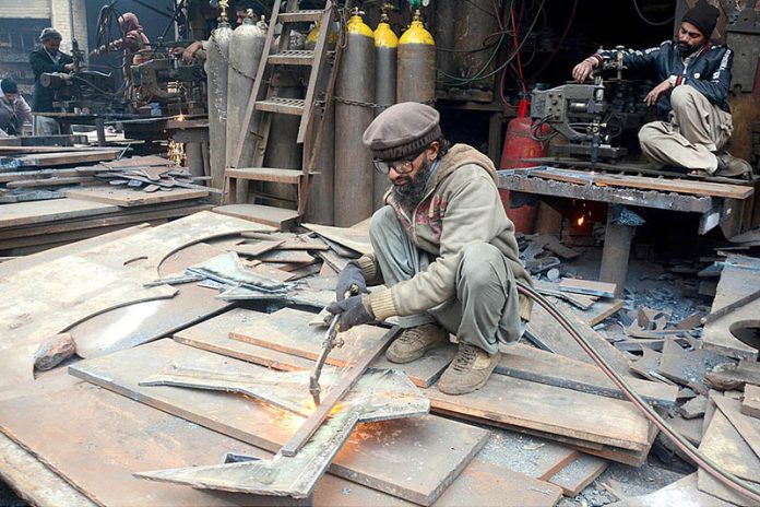 A blacksmith is cutting an iron sheet with iron cutter machine at his workshop