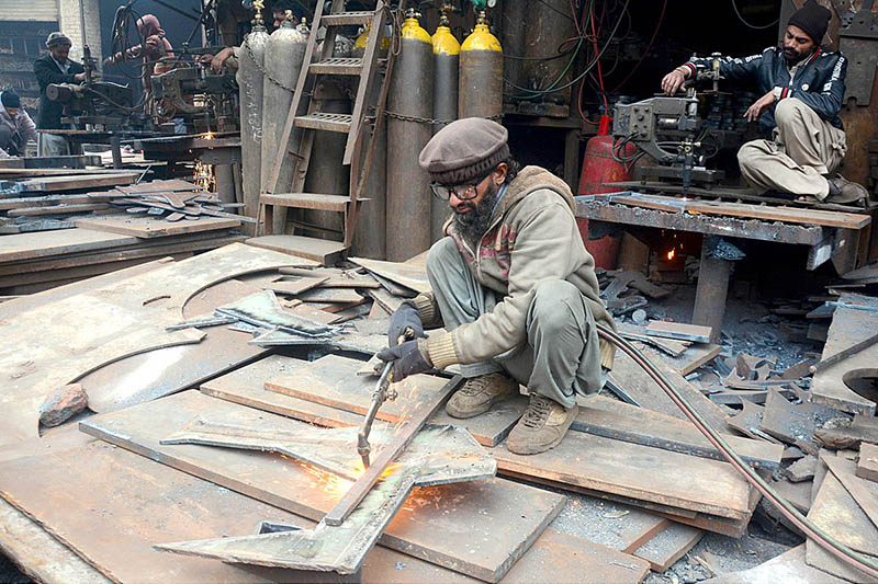 A blacksmith is cutting an iron sheet with iron cutter machine at his workshop