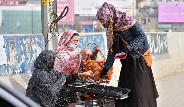 A female vendor displaying sunglasses to attract customers at Khanna Pul