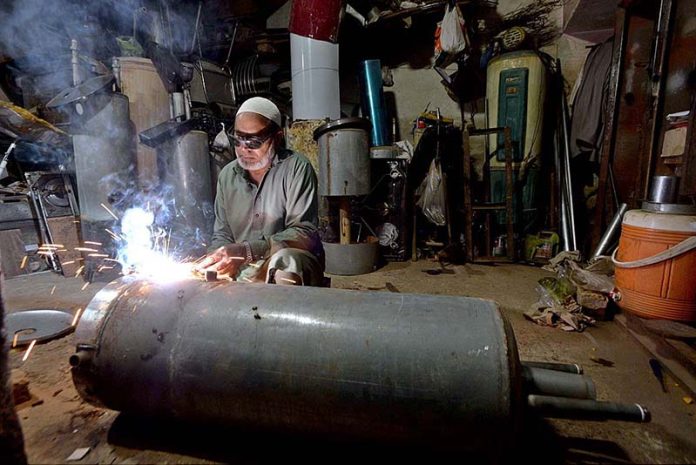 A worker welding geyser at his workshop