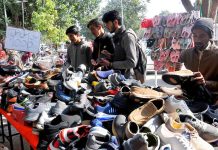 Customers are choosing and purchasing shoes on sale from roadside stalls in Federal Capital