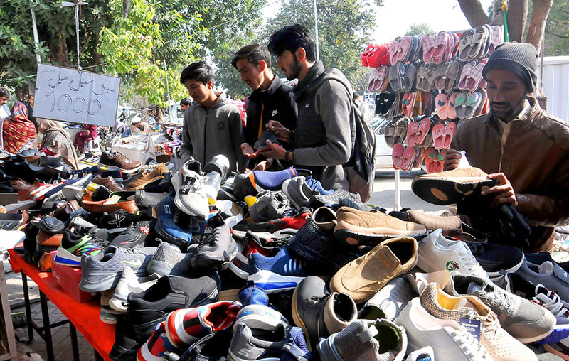 Customers are choosing and purchasing shoes on sale from roadside stalls in Federal Capital
