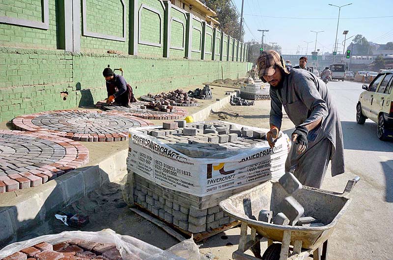 Laborers busy in construction work of footpath at Khyber road