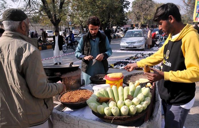 A vendor selling roasted corn to attract customers at roadside.