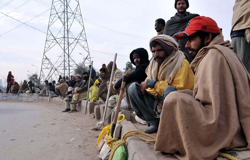 Labourers along with their tools waiting for daily wages work while sitting along road at Khana Pull.