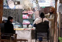 A barber busy in making the shave of a customer at his roadside setup at Ghouri Town in twin cities