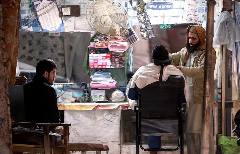 A barber busy in making the shave of a customer at his roadside setup at Ghouri Town in twin cities