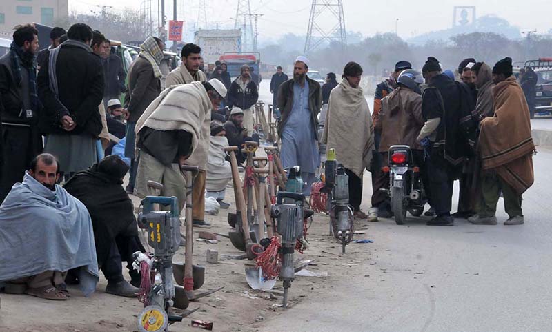 Labourers along with their tools waiting for daily wages work while sitting along road at Khana Pull.