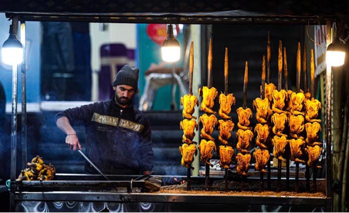 A vendor busy in roasting Balochi Sajji at his setup at Ghouri Town neighbourhood in twin cities