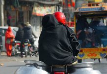 A motorcyclist on the way loaded with two cauldrons