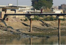 Youngsters crossing the canal by walking on the pipeline at Hala Naka Area