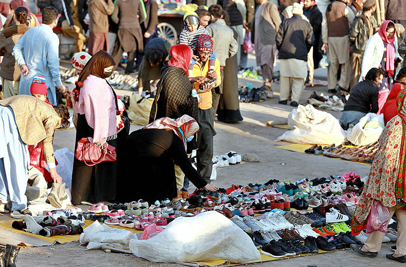 Customers selecting and purchasing second hand shoes from a vendor at Kuri Road