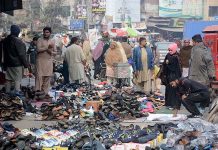 People busy in selecting and purchasing shoes at roadside stall