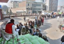 People standing in long queue to purchase wheat flour bags on subsidized rate at Sosan Road