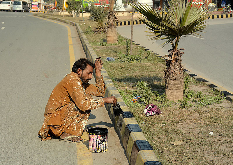 A painter is painting sidelines of a road during maintenance work in the city