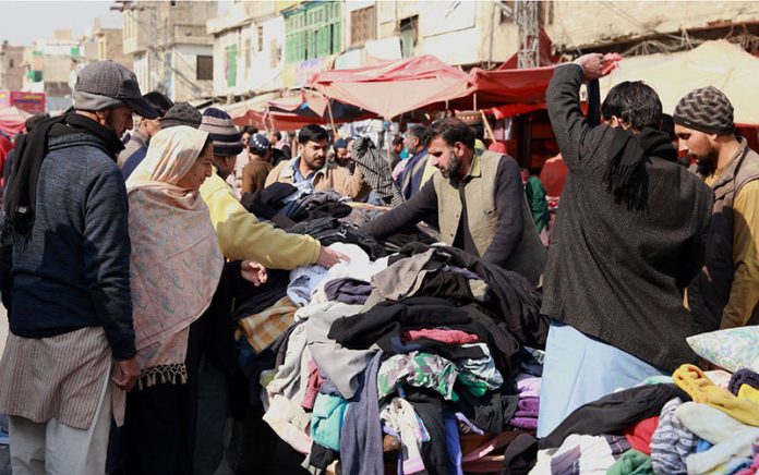 Customers busy in selecting and purchasing second hand clothes from a vendor at Raja Bazaar as the demand of warm clothes increased due to dropping temperature in twin cities