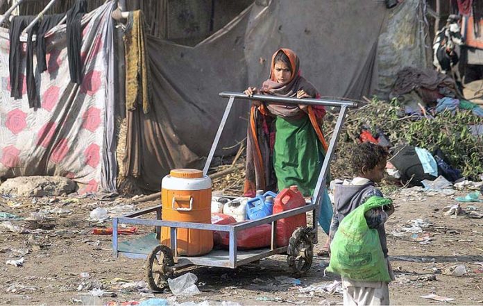 A teenage girl pushing cans on the hand cart filled with drinking water