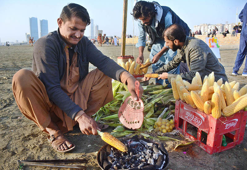 A vendor roasting corn cobs for selling at Sea view beach Clifton.