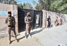 Security official standing high alert outside polling station during Local Government Elections