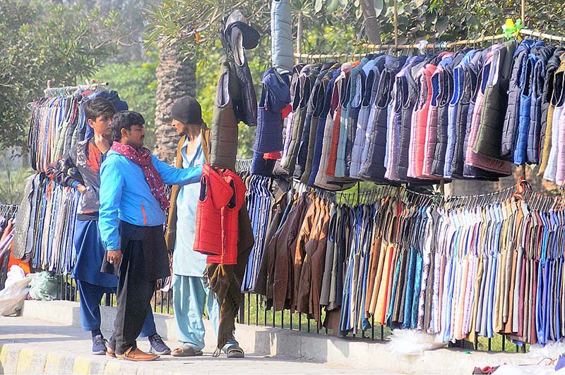 A person selecting jacket from a roadside vendor